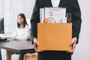 A man has been wrongfully dismissed and is leaving work with a box of his things